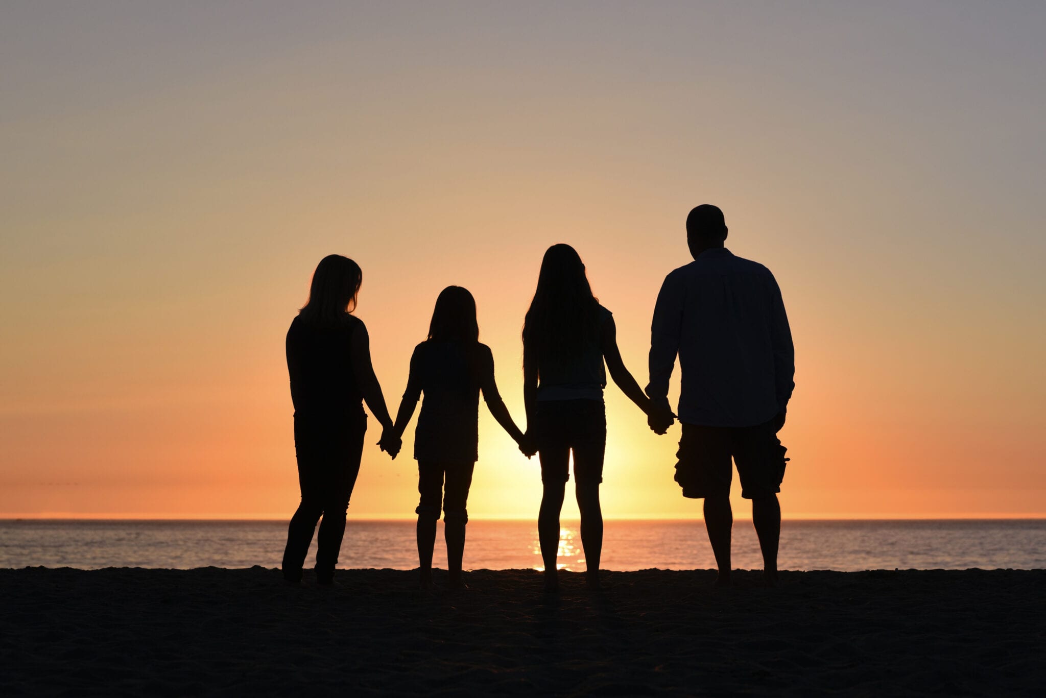 Family Standing on Shore of Beach During Sunset